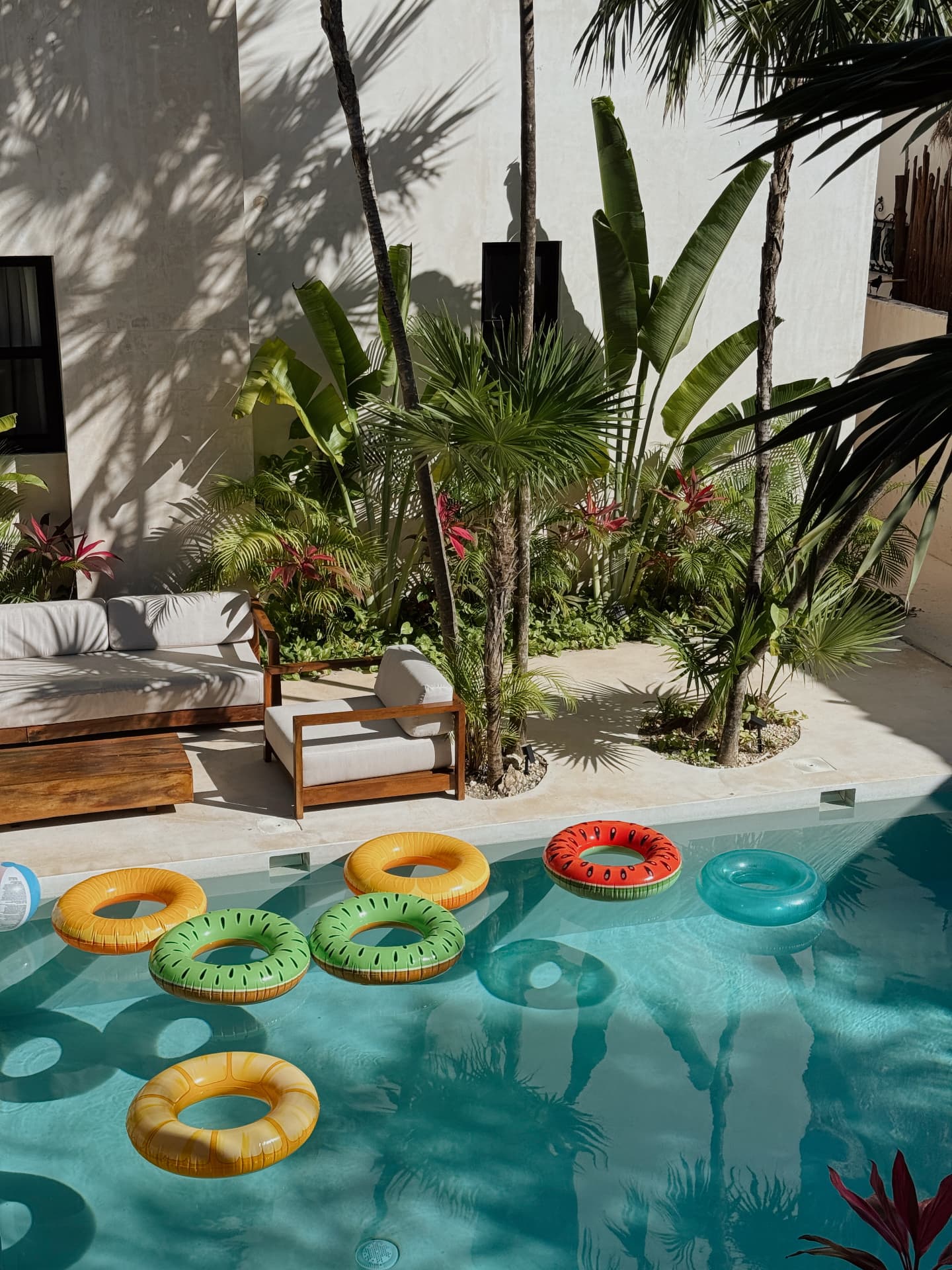 Fruit pool floats drifting in a pool beside palms