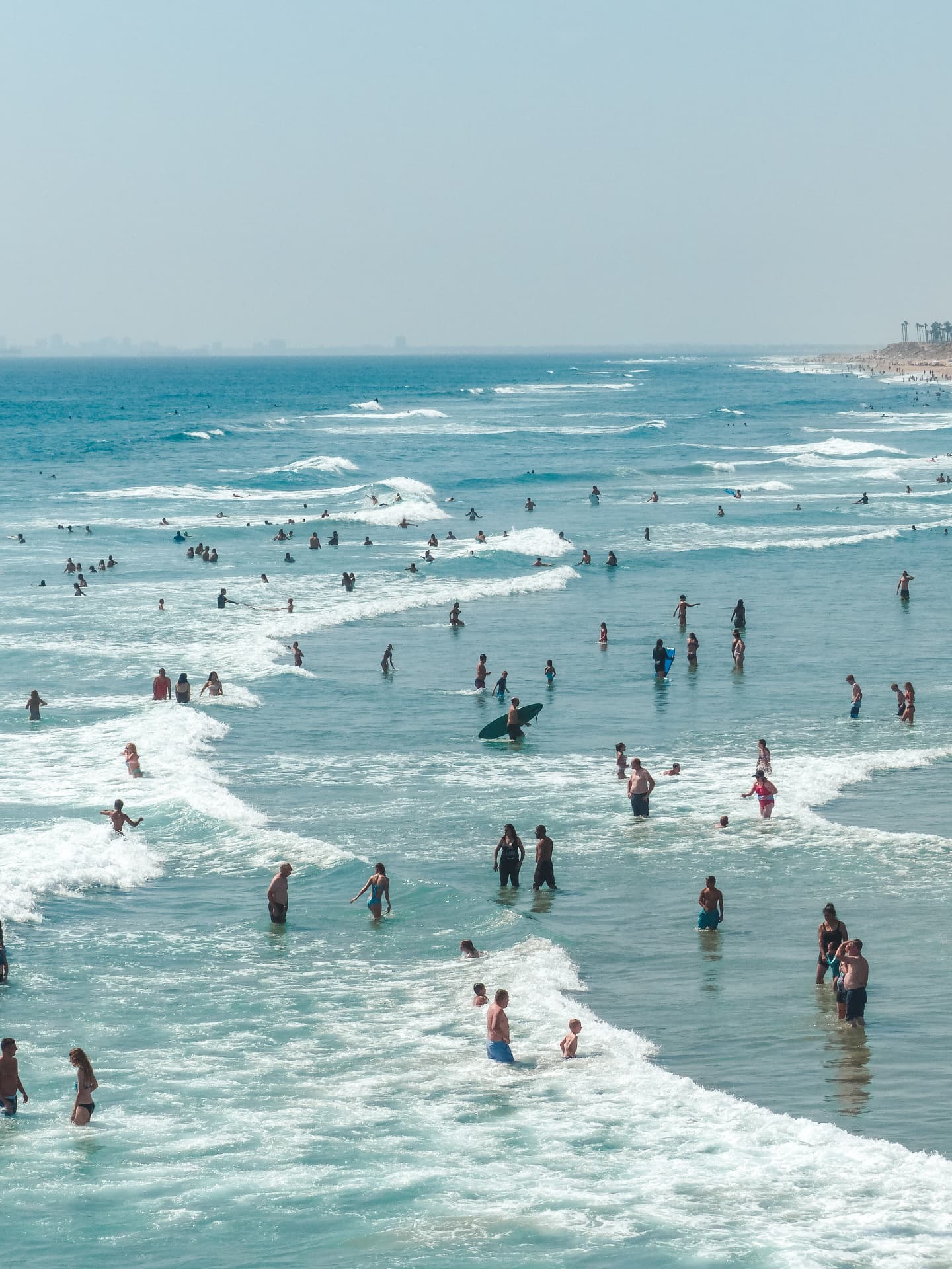 Swimmers and surfers spread along a wide shoreline